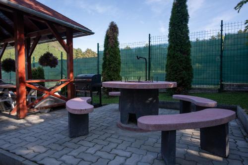 a picnic table and benches in a park at Hegyi Panzió in Szilvásvárad