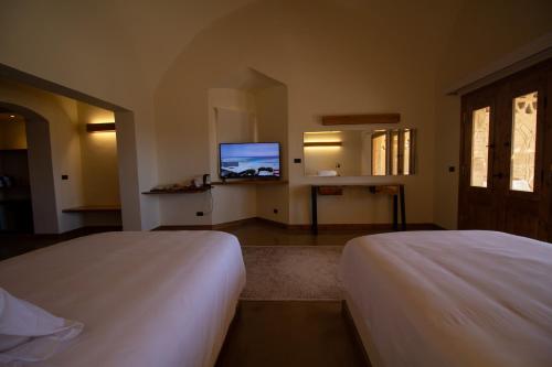 a bedroom with two beds and a flat screen tv at Marsa Shagra Village in Abu Dabab