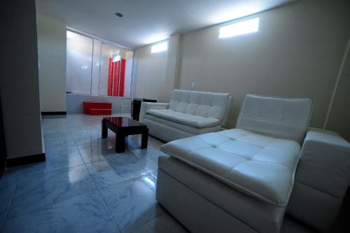 a living room with two white couches and a table at Hotel Oasys Blue in Roldanillo