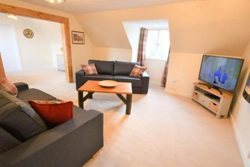 a living room with a couch and a tv at Lonan Country House and Gardens in Taynuilt