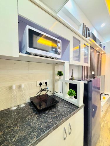 a kitchen with a counter with a microwave and a refrigerator at Blooming BNB in Greater Noida