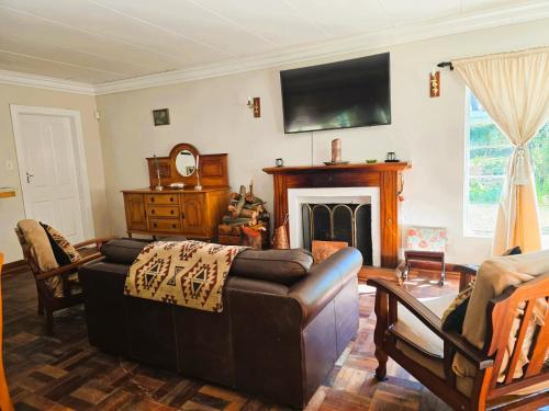 a living room with a couch and a fireplace at Dogwood Country House in Lidgetton