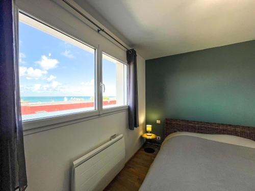 a bedroom with a bed and a window with the beach at Maison Lévi avec vue mer et à 200m du port in Digosville