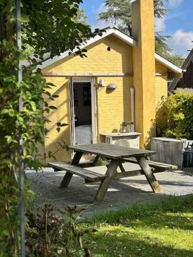 a picnic table in front of a yellow building at Cozy Little House In The Countryside in Skamby