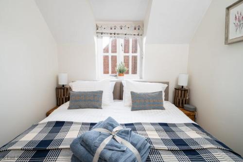 a bedroom with a bed with a blanket and a window at Dog friendly cottage with hot tub under 350 steps to dunes in Winterton-on-Sea