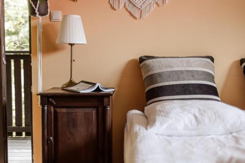 a bed with a pillow and a table with a lamp at Dom Puchacza w Lądku-Zdroju in Lądek-Zdrój