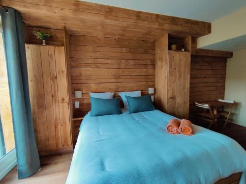 a bedroom with a large bed with blue pillows at Le Petit Oingt de Paradis Chambre d'hôtes 