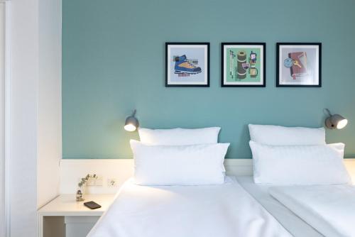 a bedroom with two white pillows and a blue wall at Garner Hotel Aschaffenburg Post by IHG in Aschaffenburg