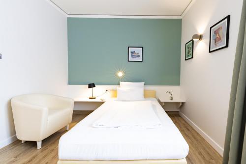 a small room with a bed and a chair at Garner Hotel Aschaffenburg Post by IHG in Aschaffenburg