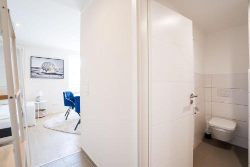 ein weißes Bad mit WC und Tür in der Unterkunft Das Solaris Beach Apartment 20 mit Garten, Sauna und hundefreundlicher Ausstattung in Grömitz