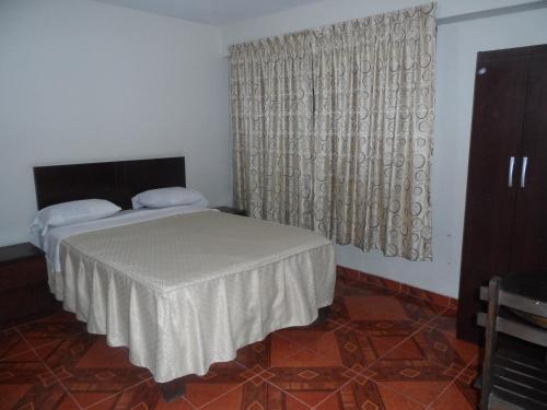 a bedroom with a bed and a window with curtains at Antares Inn in Lima