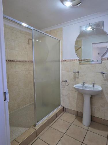 a bathroom with a glass shower and a sink at Dogwood Country House in Lidgetton