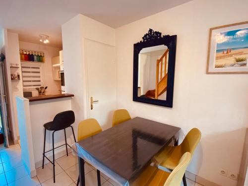 a dining room with a table and chairs and a mirror at Serena Entre mer et forêt in Camiers