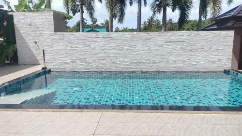 a swimming pool with a brick wall and a blue at The Horizon Villa Songkhla in Ban Mai