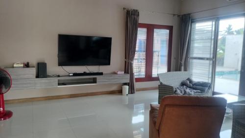 a living room with a flat screen tv and chairs at The Horizon Villa Songkhla in Ban Mai