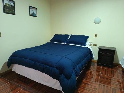 a bedroom with a blue bed and a night stand at Lodge Atacama Hostal in Copiapó