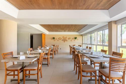 a dining room with long tables and chairs at Flat Marupiara 220 - Muro Alto, Porto de Galinhas in Porto De Galinhas