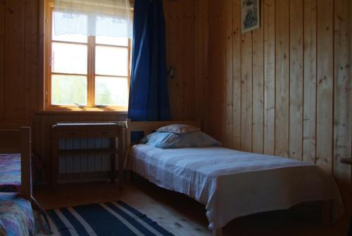 a small bedroom with a bed and a window at Stajnia Okliny in Wiżajny