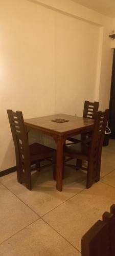 Una mesa de madera con cuatro sillas alrededor. en Wije House, en Dikwella