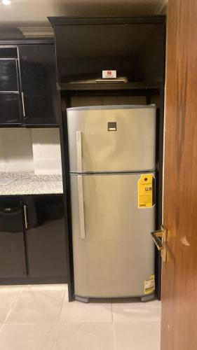 a stainless steel refrigerator in a kitchen with black cabinets at Zm apartment shehab Vib in Cairo
