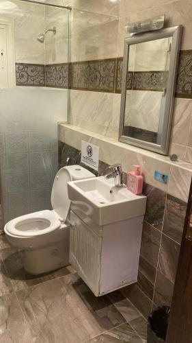 a bathroom with a toilet and a sink and a mirror at Zm apartment shehab Vib in Cairo
