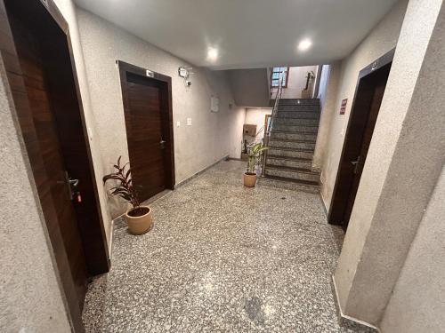 a hallway with stairs and potted plants in a building at Hotel Postcard in Pālampur