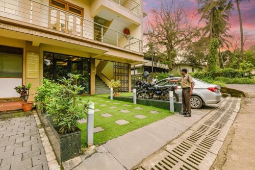 a man standing next to a car in front of a house at FabHotel Prime Swarnam, Old Goa in Old Goa
