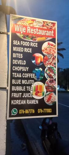 a sign on the side of a building with a menu at Wije House in Dickwella