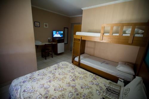 a bedroom with two bunk beds and a television at Hotel Estação Paraíso - ao lado do Metrô Paraíso e 600m da Av Paulista in Sao Paulo