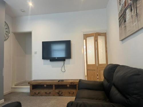 a living room with a couch and a flat screen tv at George Guest House in Stoke on Trent