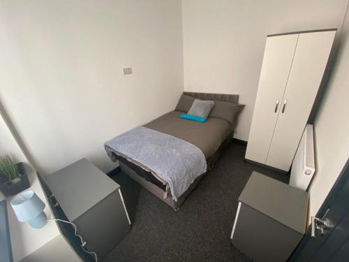 a small bedroom with a bed and two cabinets at George Guest House in Stoke on Trent