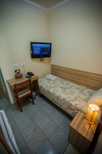 a bedroom with a bed and a tv on the wall at Hotel Estação Paraíso - ao lado do Metrô Paraíso e 600m da Av Paulista in Sao Paulo