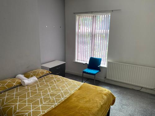a bedroom with a bed and a blue chair and a window at George Guest House in Stoke on Trent