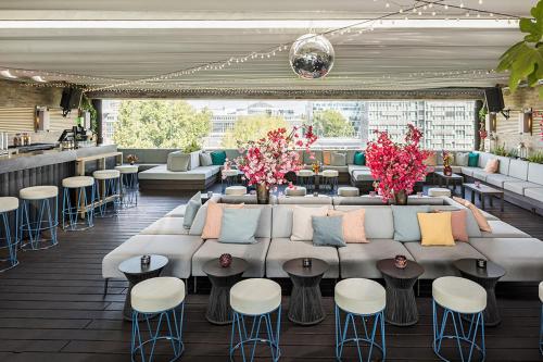 a living room with a couch and tables and chairs at Hotel AMANO East Side in Berlin