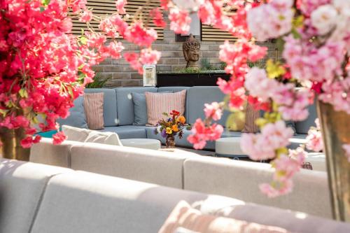 a group of white couches and pink flowers at Hotel AMANO East Side in Berlin