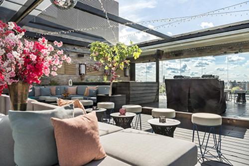 a patio with couches and tables and flowers at Hotel AMANO East Side in Berlin