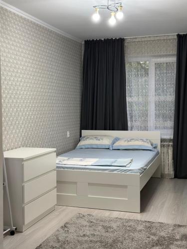 a bedroom with a bed and a window at Квартира в районе Esentai Mall in Almaty
