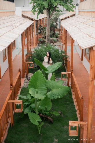 a woman sitting in the middle of a building with plants at Lá Nhỏ Homestay Mộc Châu in Mộc Châu