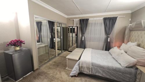Un dormitorio con una cama y un espejo grande. en Villa on the East-Party House, en Boksburg