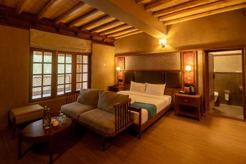 a bedroom with a bed and a couch and a chair at Hotel The Kaal in Leh