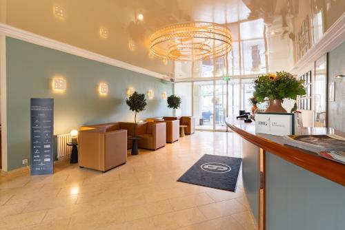 a lobby with a waiting area with chairs and a chandelier at Garner Hotel Aschaffenburg Post by IHG in Aschaffenburg