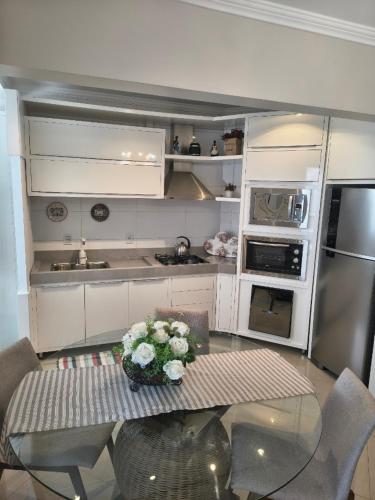 eine Küche mit einem Tisch mit Blumen darauf in der Unterkunft Apartamento aconchegante com ar, secadora e adega in Piratuba
