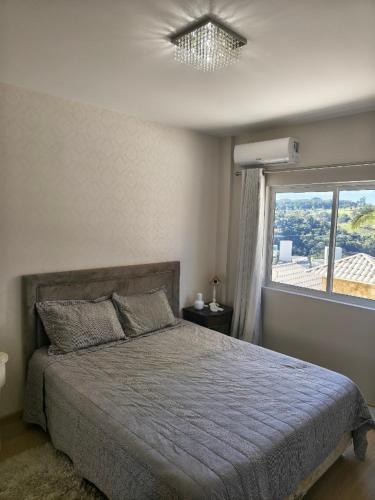 ein Schlafzimmer mit einem Bett und einem großen Fenster in der Unterkunft Apartamento aconchegante com ar, secadora e adega in Piratuba