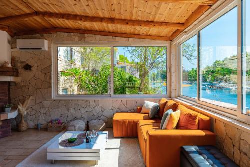 a living room with an orange couch and large windows at Apartman Mirakul in Korčula