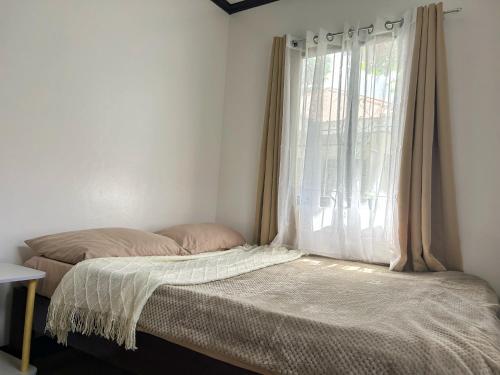 una cama en una habitación con ventana en Frankies Island Home, en General Luna