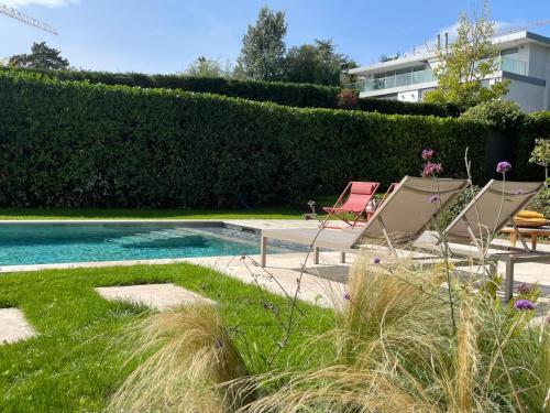 a swimming pool with two lawn chairs next to it at 'Le Petit Clos Suites'- Charming Getaway on Leman Lake in Nyon