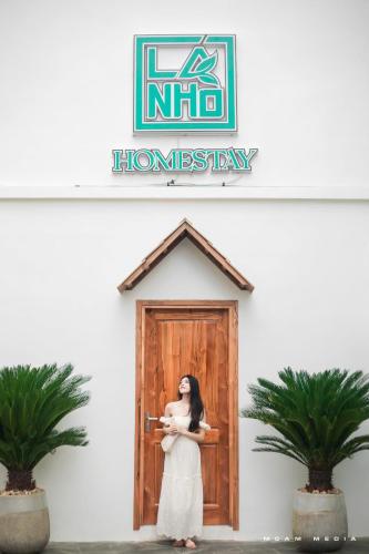 a woman standing in front of a wooden door at Lá Nhỏ Homestay Mộc Châu in Mộc Châu