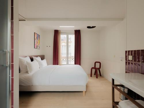 a bedroom with a white bed and a window at Edgar Suites - Lemercier in Paris