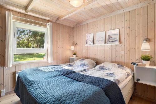 a bedroom with a bed with a blue comforter and a window at HA385-Hals-Sonder-Havsig-8 in Hou