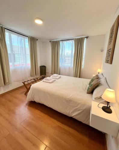 una camera da letto con un grande letto bianco e due finestre di Amplio departamento renovado en el centro de la ciudad a El Calafate